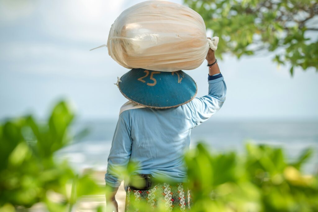 Person with their back to the camera carrying a large bag over their head